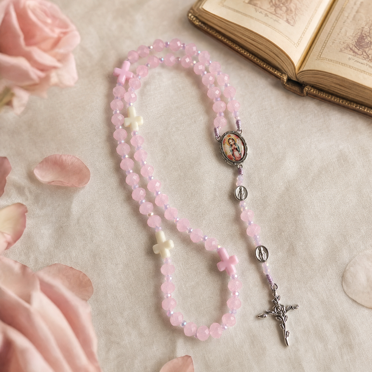 Rosario tradicional rosado sobre lino con libro de oraciones